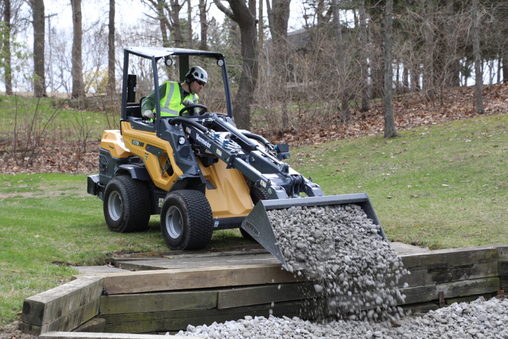 Vermeer ATX720 pouring rock into landscape project